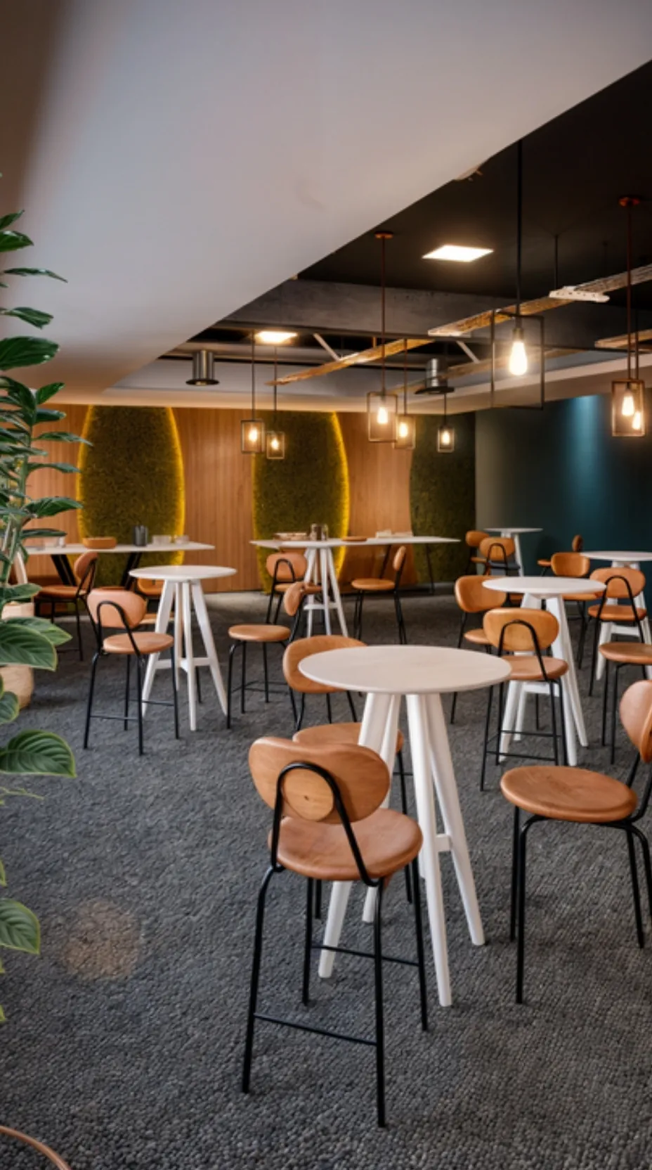 Lounge com mesas altas, cadeiras de madeira e luz baixa